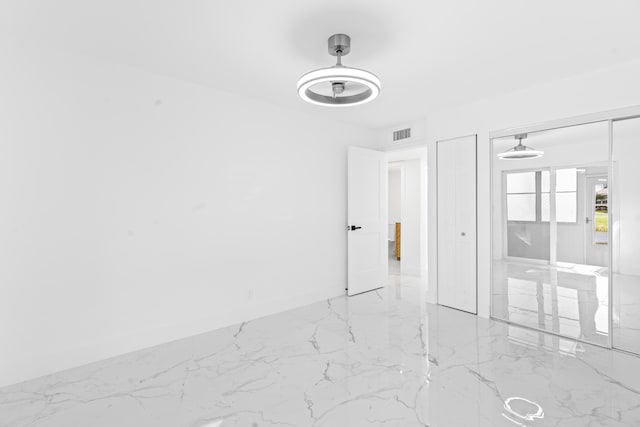 unfurnished bedroom featuring a closet, marble finish floor, visible vents, and baseboards