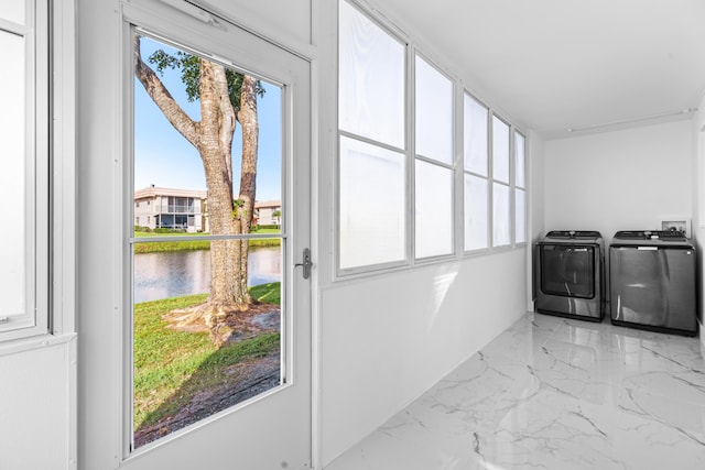 clothes washing area with marble finish floor, laundry area, a water view, and washer and dryer