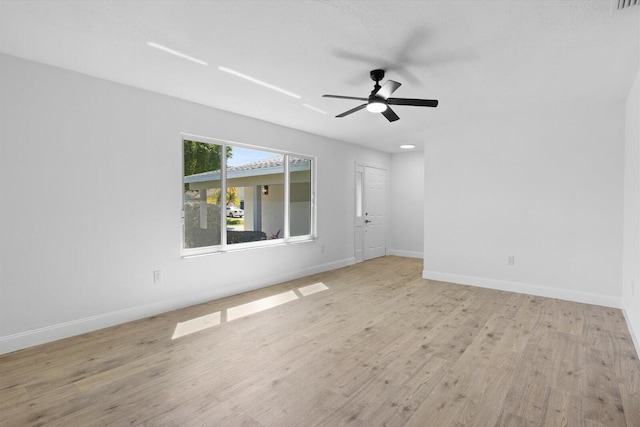 unfurnished room with wood finished floors, a ceiling fan, and baseboards