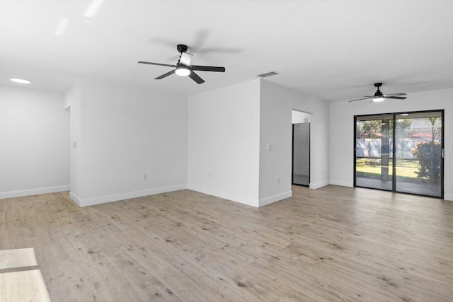 spare room with a ceiling fan, light wood-type flooring, visible vents, and baseboards