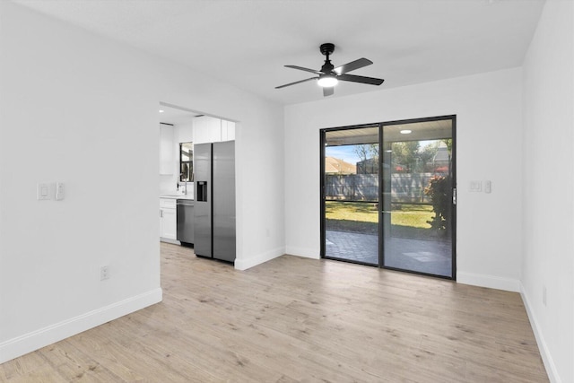 spare room with light wood-type flooring, ceiling fan, and baseboards