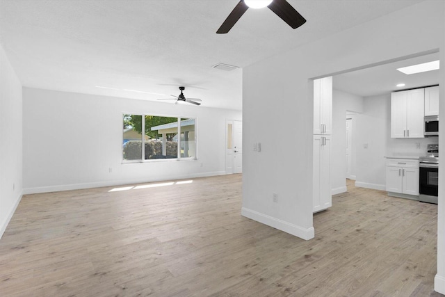 unfurnished living room featuring a ceiling fan, light wood-style flooring, visible vents, and baseboards