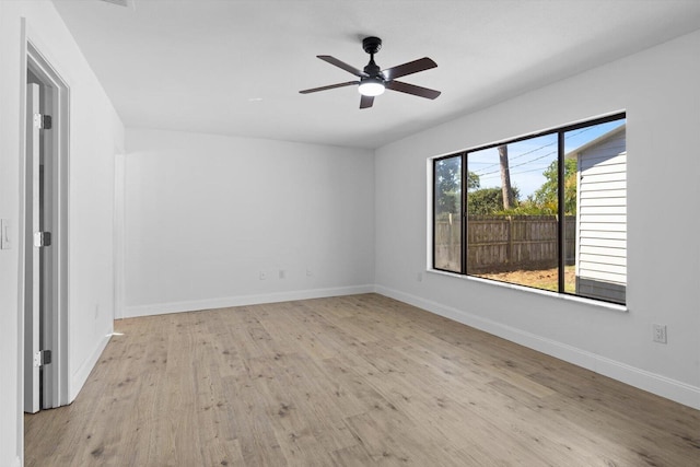 empty room with wood finished floors, a ceiling fan, and baseboards