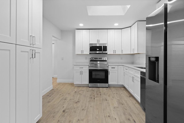 kitchen with appliances with stainless steel finishes, white cabinets, light countertops, and light wood finished floors