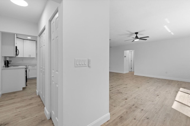 corridor with light wood-type flooring and baseboards