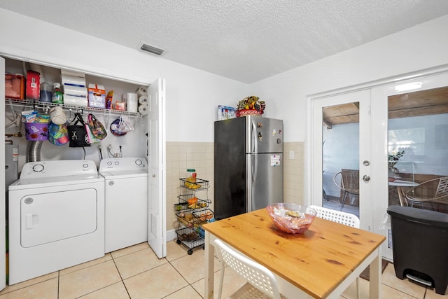 washroom featuring tile walls, laundry area, light tile patterned flooring, washer and dryer, and a textured ceiling