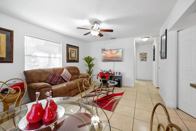 living room featuring ceiling fan, light tile patterned flooring, baseboards, and a textured ceiling