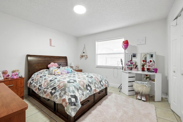 bedroom featuring light tile patterned flooring, a textured ceiling, and baseboards