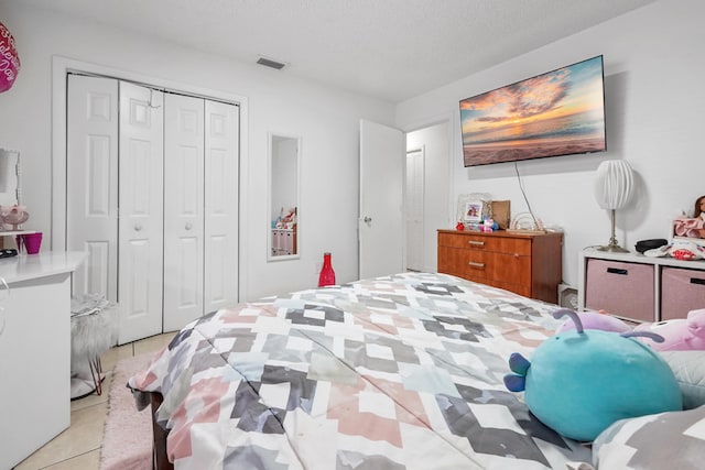 bedroom with light tile patterned floors, a closet, a textured ceiling, and visible vents