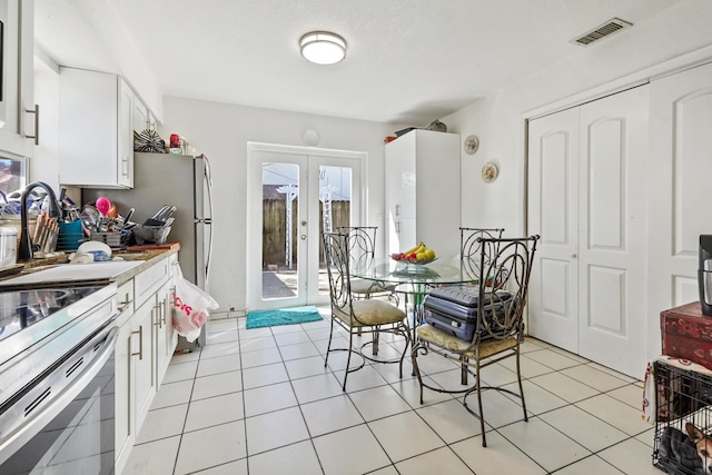 dining space with light tile patterned flooring, french doors, and visible vents