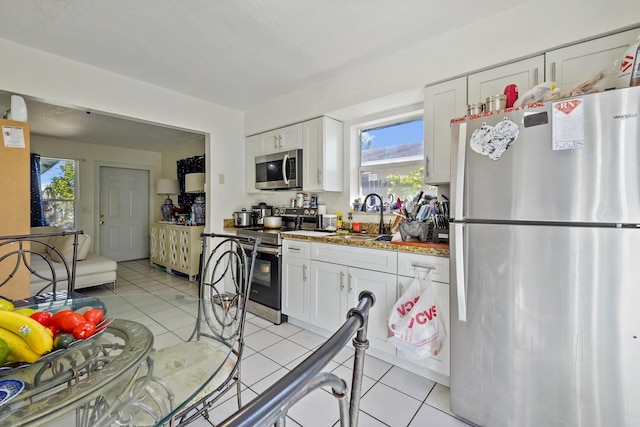 kitchen featuring a sink, white cabinets, light tile patterned floors, and stainless steel appliances