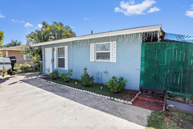 view of front of house featuring stucco siding, a patio, and fence