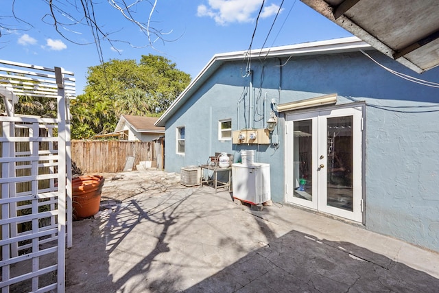 rear view of property with fence, stucco siding, french doors, a pergola, and a patio