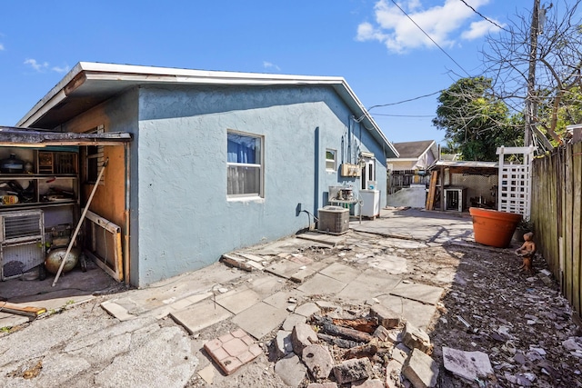 rear view of property featuring stucco siding, a patio, central air condition unit, and fence