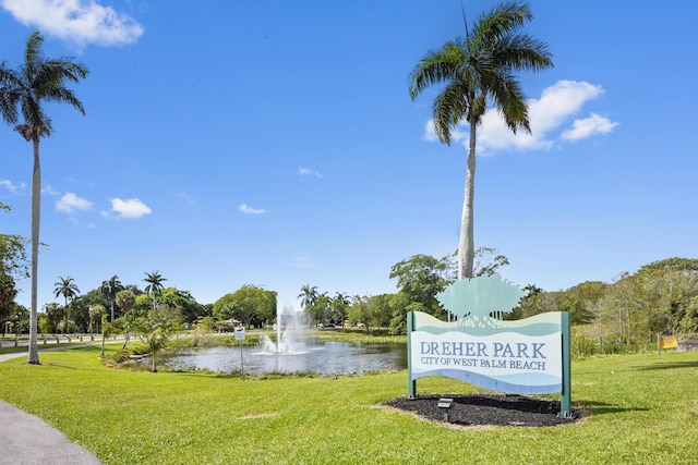 community sign featuring a yard and a water view