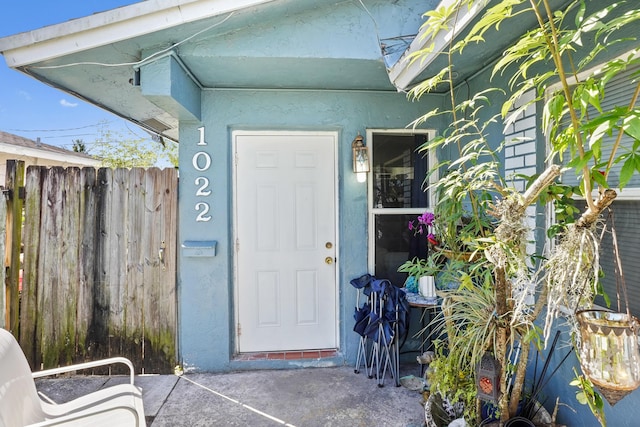 property entrance featuring stucco siding and fence