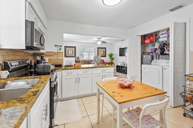 1022 Green St, West Palm Beach, FL 33405 - kitchen with appliances with stainless steel finishes, washing machine and clothes dryer, a peninsula, light tile patterned floors, and a textured ceiling