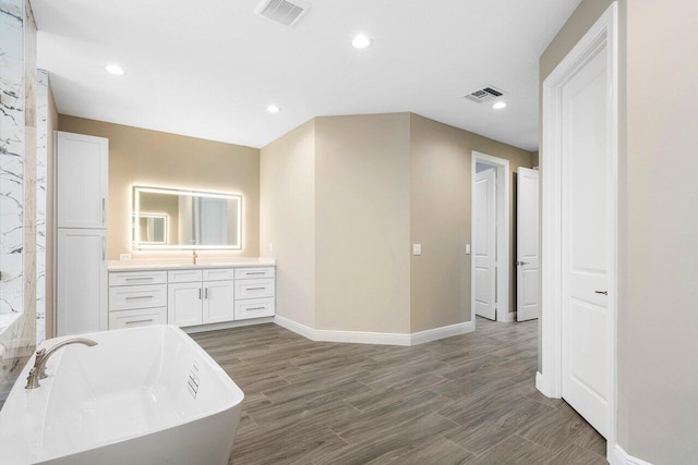 full bath featuring a freestanding tub, visible vents, vanity, and wood finished floors