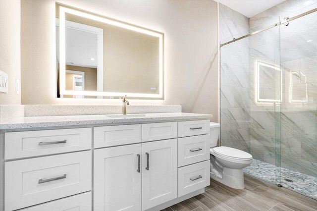 bathroom featuring vanity, a marble finish shower, and toilet