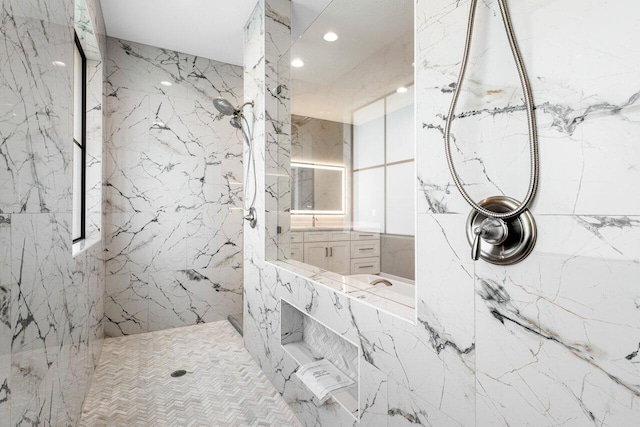 bathroom featuring stone wall, recessed lighting, a marble finish shower, and vanity