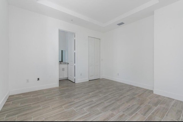 unfurnished room with wood finish floors, a raised ceiling, visible vents, and baseboards