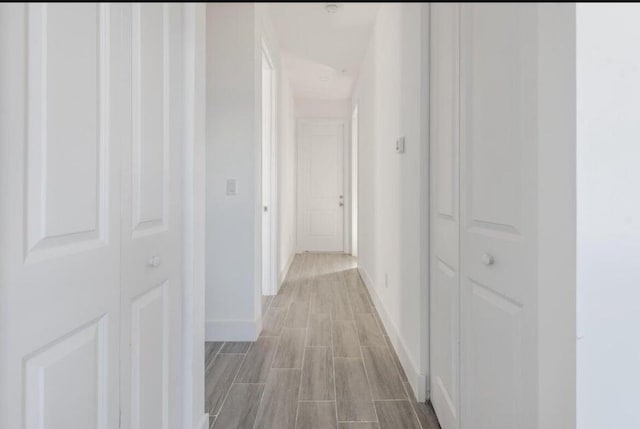 hall featuring wood tiled floor and baseboards