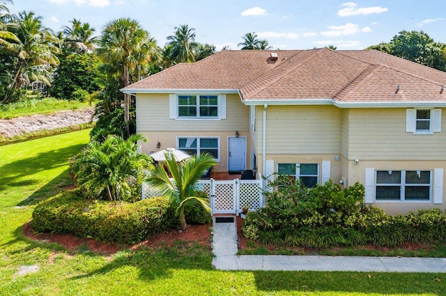 view of front of property with a front lawn, a shingled roof, and stucco siding