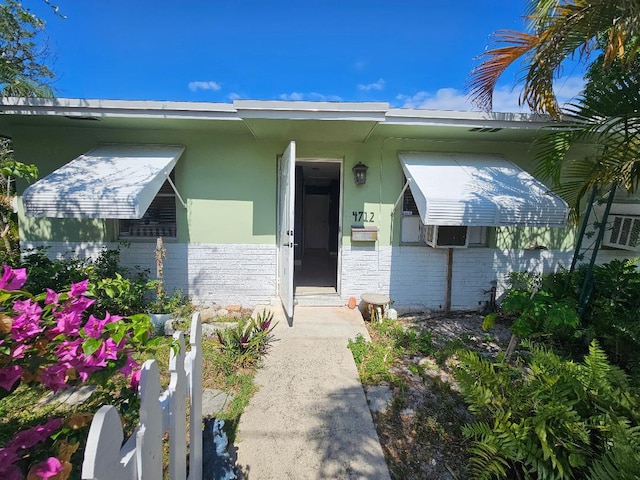 view of exterior entry featuring brick siding and stucco siding