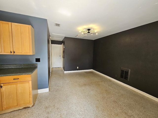 interior space with dark countertops, light brown cabinets, visible vents, and light speckled floor