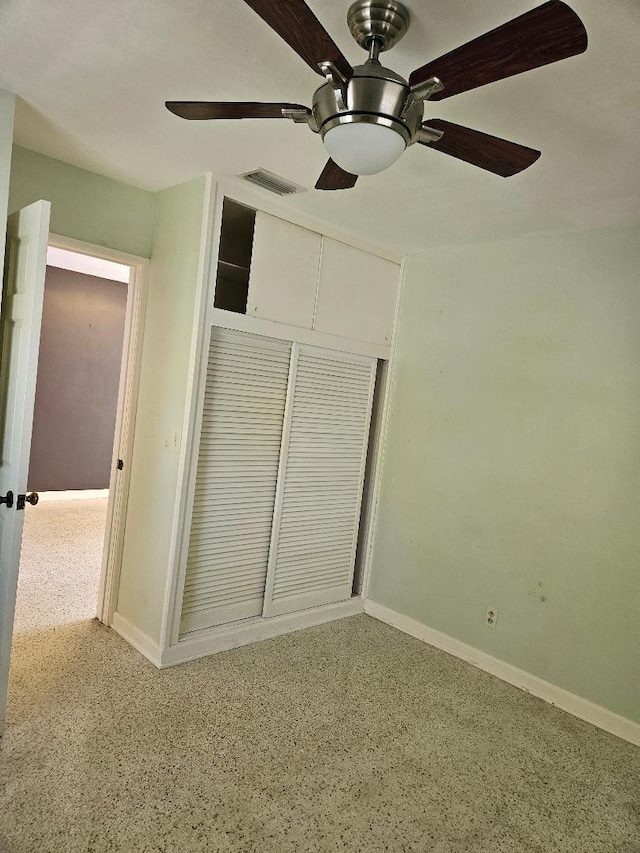 unfurnished bedroom with speckled floor, a ceiling fan, visible vents, baseboards, and a closet