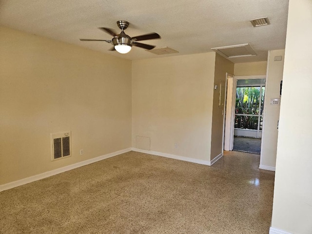 unfurnished room featuring attic access, visible vents, a textured ceiling, and speckled floor