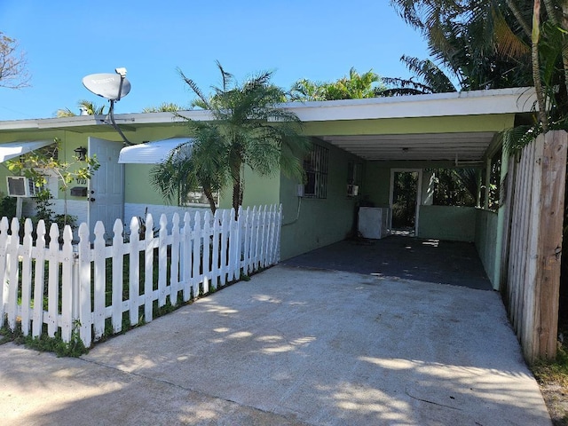 view of property exterior featuring a carport, concrete driveway, and fence