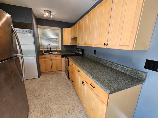 kitchen featuring light brown cabinets, a sink, appliances with stainless steel finishes, stacked washing maching and dryer, and dark countertops