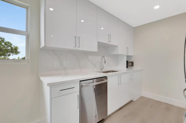 kitchen with a sink, tasteful backsplash, white cabinetry, appliances with stainless steel finishes, and baseboards