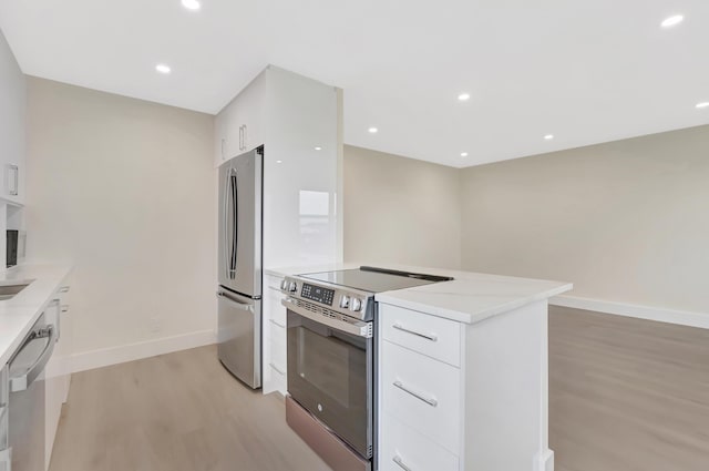 kitchen with light wood finished floors, white cabinets, appliances with stainless steel finishes, and modern cabinets