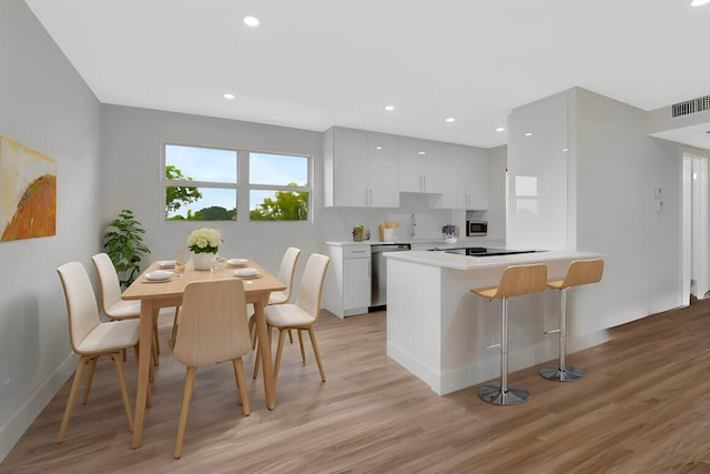 kitchen with visible vents, appliances with stainless steel finishes, a peninsula, and light wood-style floors