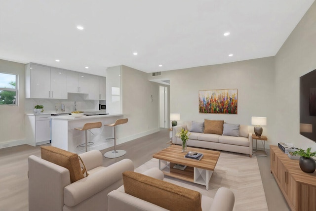 living area with light wood finished floors, visible vents, recessed lighting, and baseboards