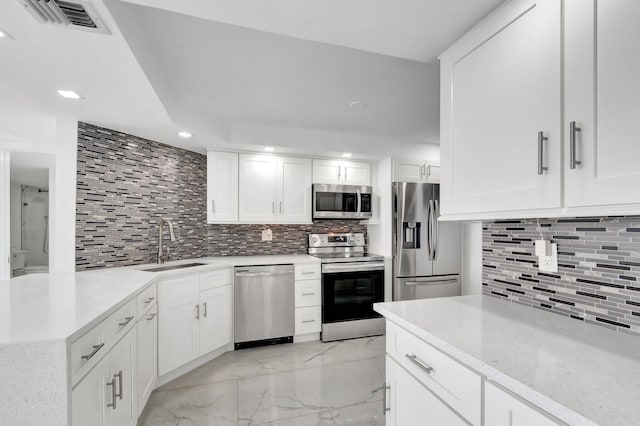 kitchen featuring marble finish floor, white cabinetry, stainless steel appliances, and a sink