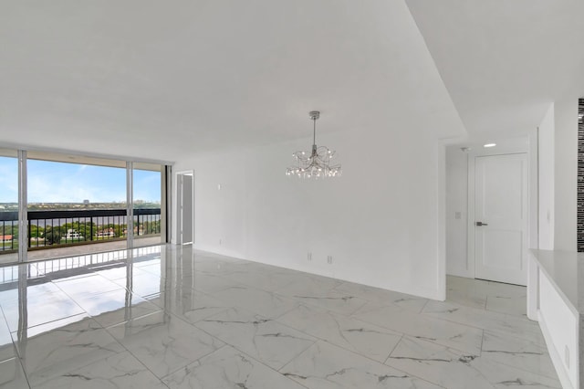 unfurnished room with expansive windows, marble finish floor, and an inviting chandelier