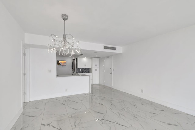 unfurnished living room featuring marble finish floor, visible vents, a notable chandelier, and baseboards