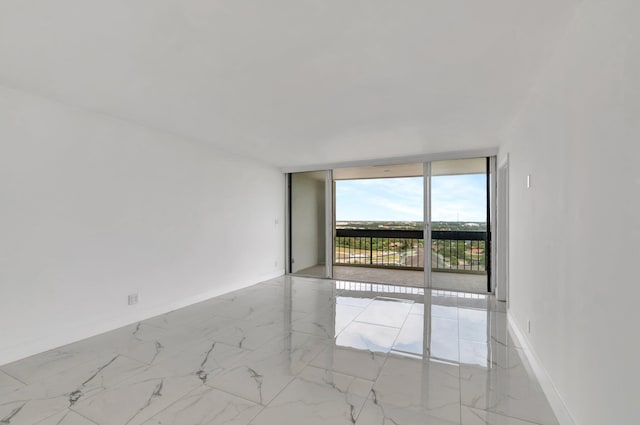 spare room with expansive windows, marble finish floor, and baseboards