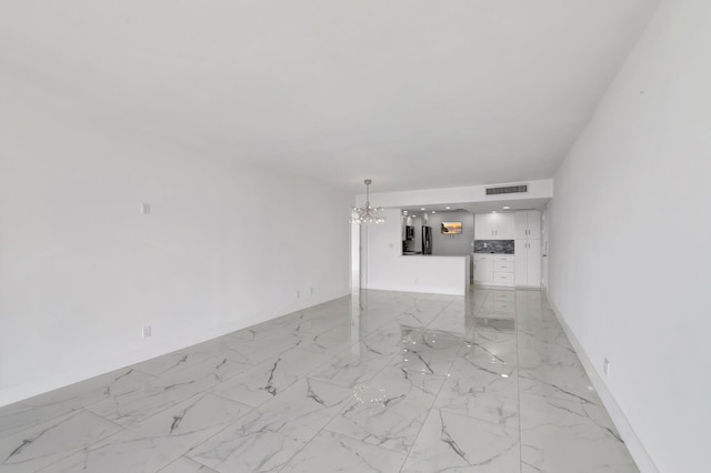 unfurnished living room with marble finish floor, visible vents, a notable chandelier, and baseboards