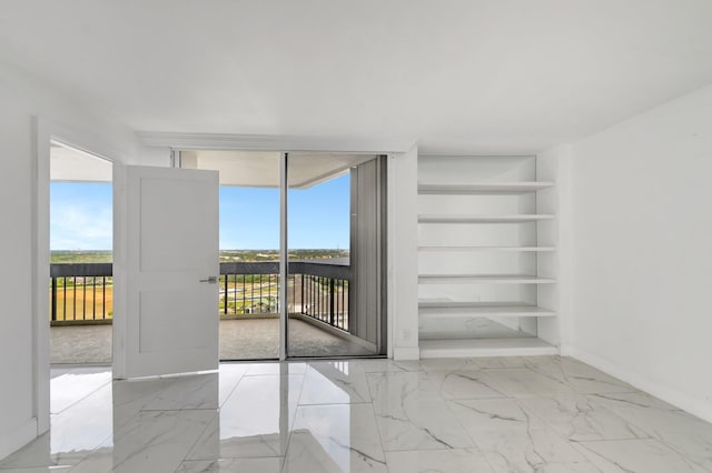 empty room featuring marble finish floor, a wall of windows, a wealth of natural light, and built in features