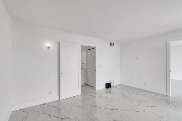 spare room with marble finish floor, visible vents, and baseboards