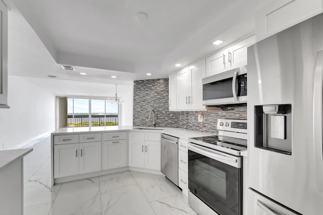 kitchen featuring stainless steel appliances, light countertops, backsplash, a sink, and a peninsula