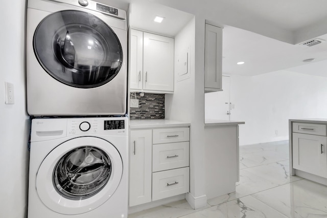 clothes washing area with marble finish floor, recessed lighting, cabinet space, visible vents, and stacked washer / dryer