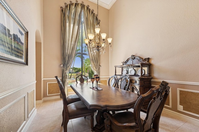 dining room featuring ornamental molding, wainscoting, an inviting chandelier, arched walkways, and a decorative wall