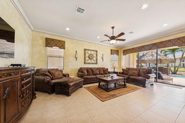 living room featuring light tile patterned floors, a ceiling fan, visible vents, and ornamental molding