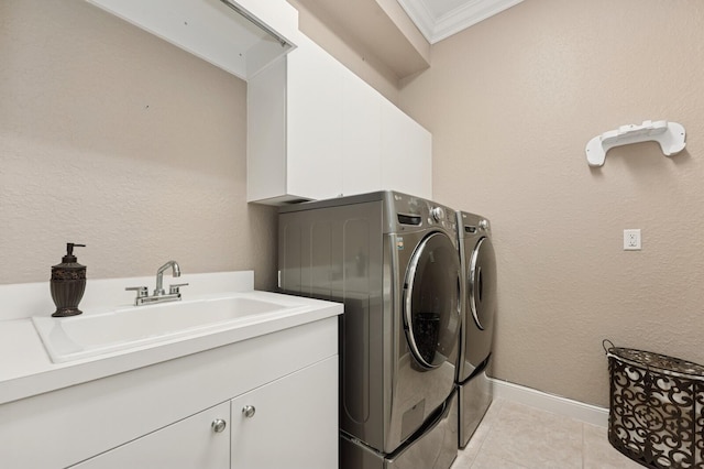 laundry area featuring light tile patterned floors, cabinet space, a sink, ornamental molding, and washer and clothes dryer