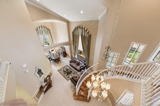 stairway featuring arched walkways, a towering ceiling, and crown molding